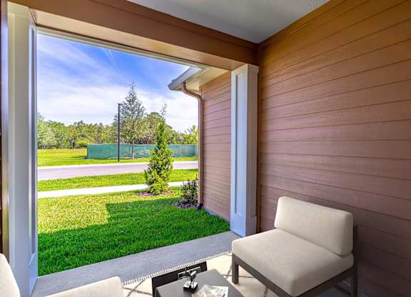A chair is on a patio with a table and a window.
