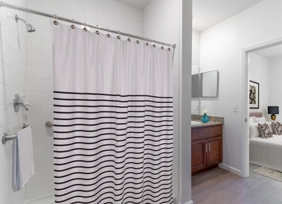 a bathroom with a shower curtain and a sink and a bedroom
