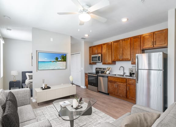 a living room with a couch and a table and a kitchen with a refrigerator