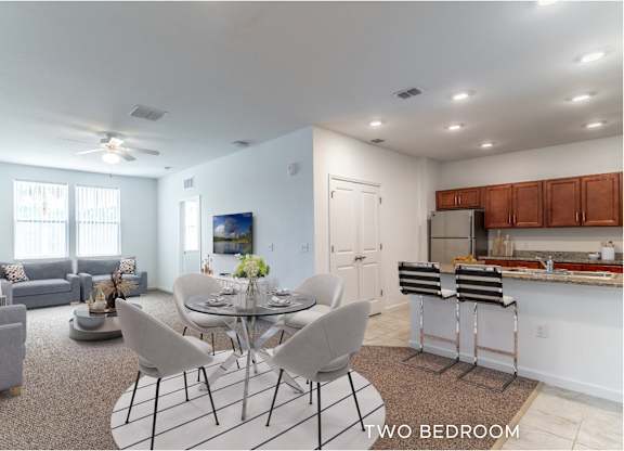 A well-lit two-bedroom apartment with a kitchen and dining area.