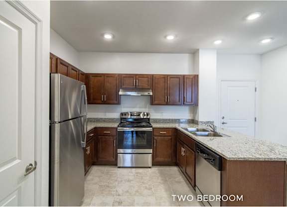 A kitchen with a refrigerator, oven, and sink.