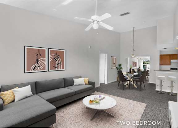 A living room with a grey couch and two zebra pictures on the wall.