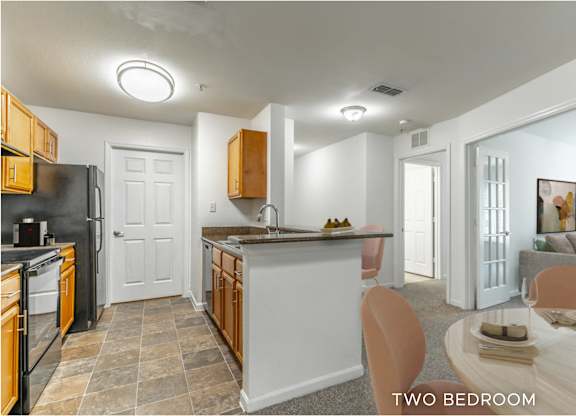 A kitchen with a black refrigerator and wooden cabinets.