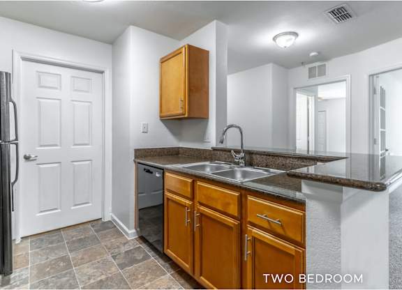 A kitchen with a sink, refrigerator, and cabinets.
