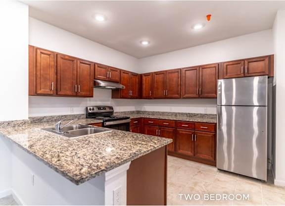 A kitchen with granite countertops and a stainless steel refrigerator.