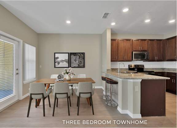A kitchen with brown cabinets and a dining table with four chairs.