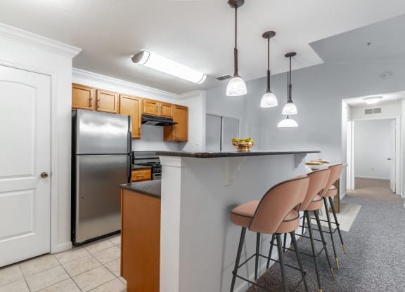 a kitchen with a bar with chairs and a refrigerator