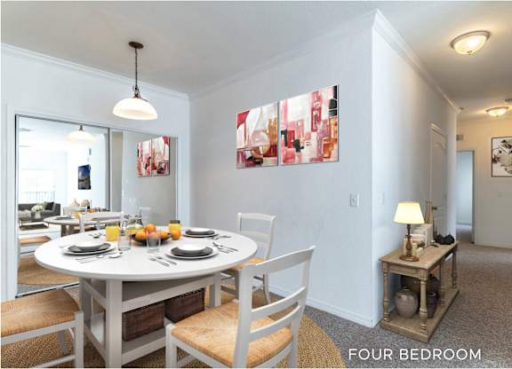 A dining room with a table set for four.
