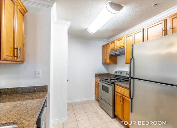 A kitchen with a refrigerator, stove, and cabinets.