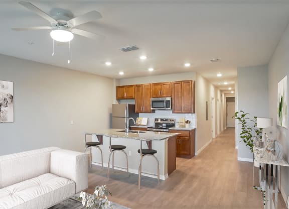 a living room with a kitchen and a ceiling fan