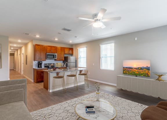 a living room with a kitchen and a ceiling fan