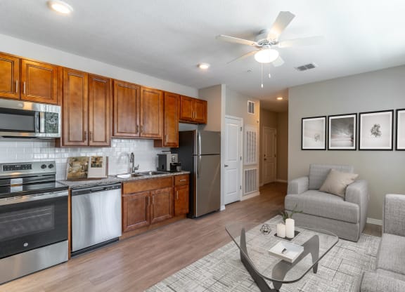 a living room with a kitchen and a ceiling fan