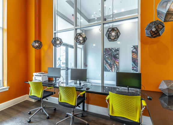 an office with orange walls and a black desk with yellow chairs