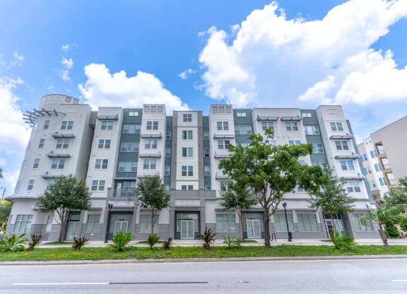 a story apartment building with trees in front of it and a blue sky in the background
