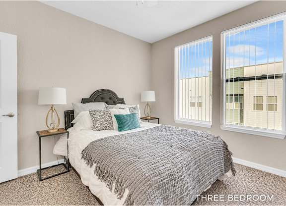 A bedroom with a bed, two lamps, and a window.