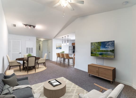 a living room with a tv and a dining room in the background