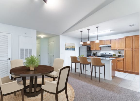 a dining area with a table and chairs and a kitchen in the background