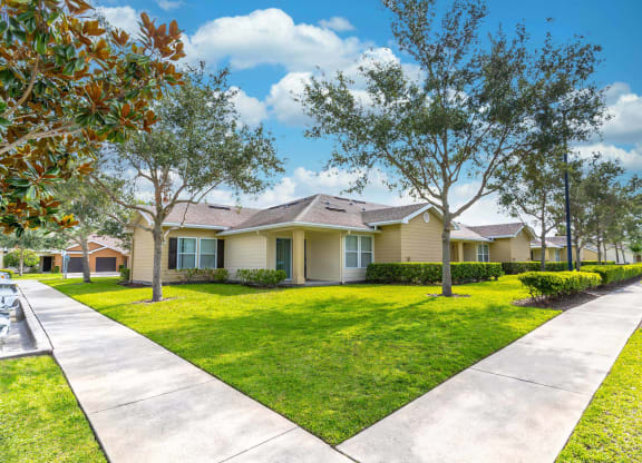 a home at Boca Townhomes with a lawn and trees in front of it