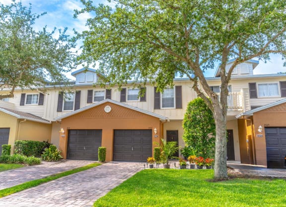a townhome with two garages and a tree in front of it
