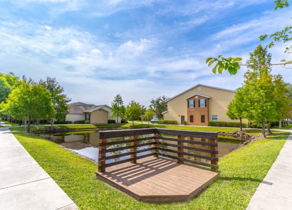 a wooden bridge over a pond with houses in the background