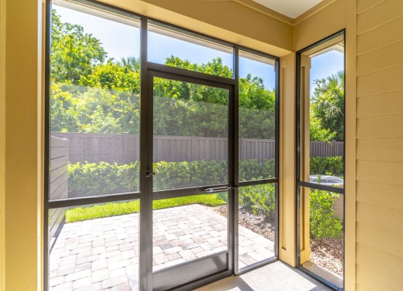 a large sliding glass door opens to a patio with a brick walkway