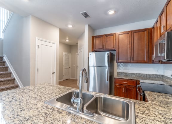 a kitchen with granite countertops and a stainless steel refrigerator