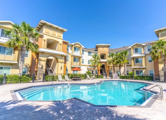 a swimming pool with palm trees in front of a building