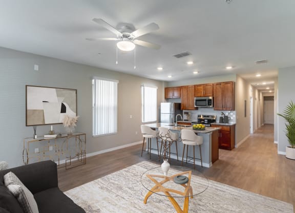 a living room with a kitchen and a ceiling fan