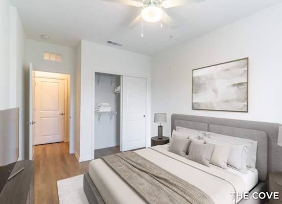 A bedroom with a bed, nightstand, and a painting on the wall.