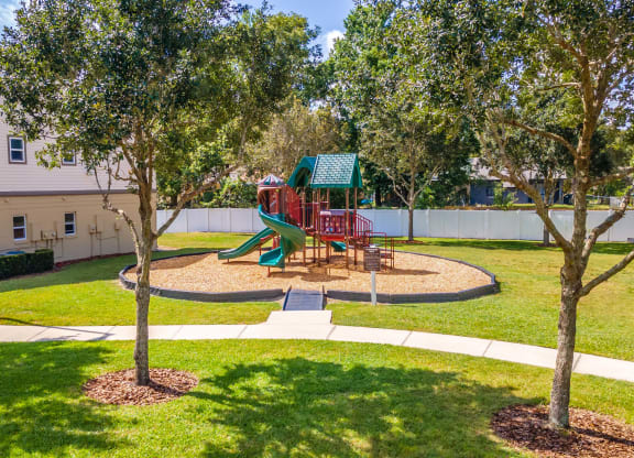 a playground with a slide in the middle of a grassy area