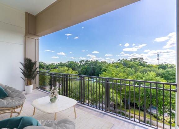 a living room with a balcony and a view of trees