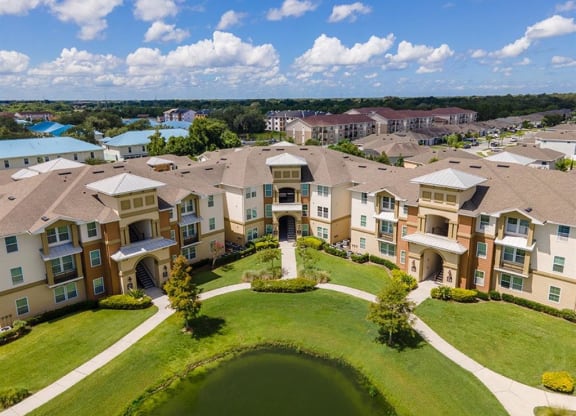 an aerial view of an apartment complex with a small pond in the middle