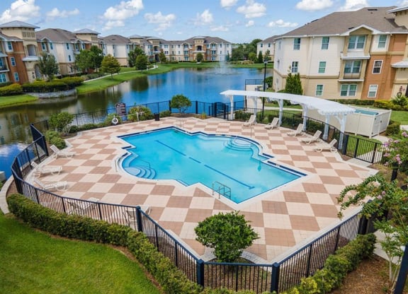 an aerial view of a swimming pool with patio furniture and a pergola in front of