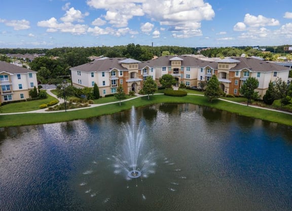 a fountain in the middle of a pond with apartment buildings in the background