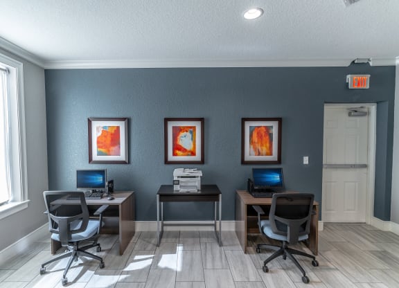 two computers and two chairs in a room with a window