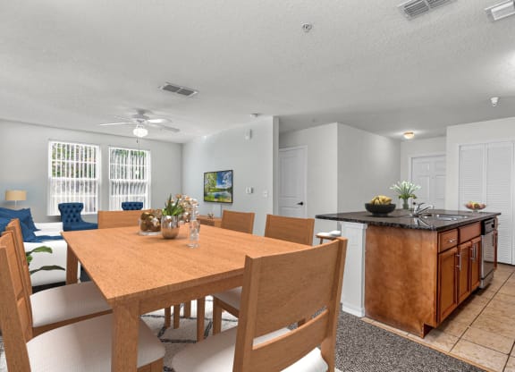 a dining area with a wooden table and chairs and a kitchen with a black counter top and