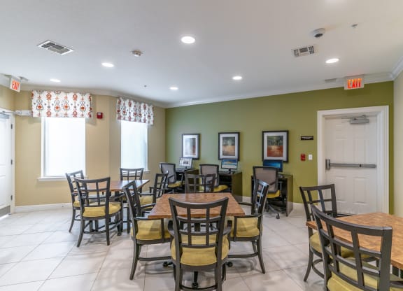 a seating area with tables and chairs at the whispering winds apartments in pearland