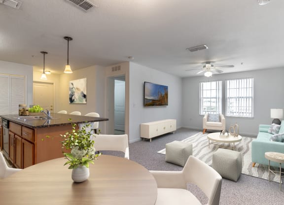 a living room with a table and chairs and a kitchen with an island