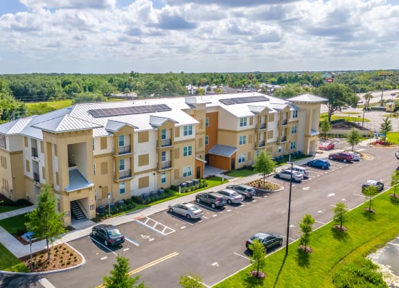 an aerial view of a large apartment complex with a parking lot and trees in the background