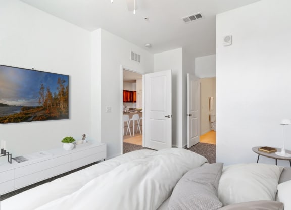 a bedroom with a large white bed and a white dresser with a potted plant