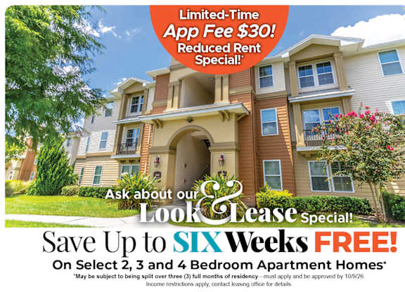 A large, multi-story apartment building with a sign offering a limited-time app fee discount and rent special.