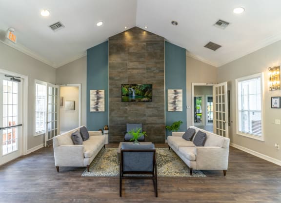 a clubhouse room with couches chairs tv and a coffee table