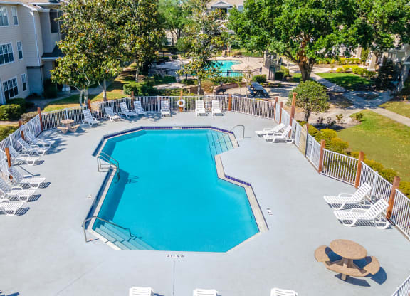 an aerial view of the resort style pool with chaise lounge chairs and trees in the background