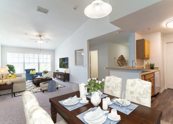 a living room with a dining table and a kitchen in the background