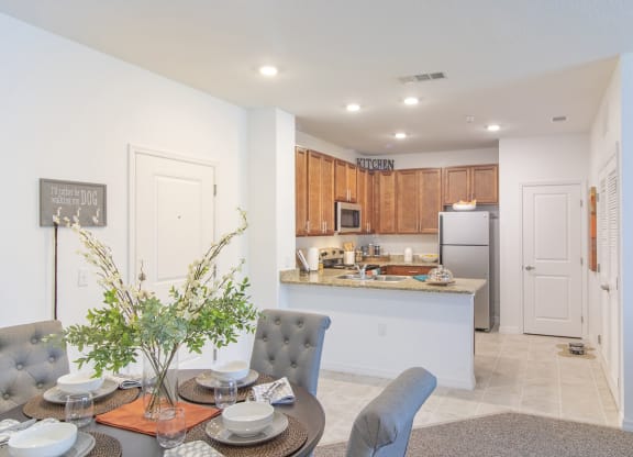 a dining area with a table and chairs and a kitchen in the background