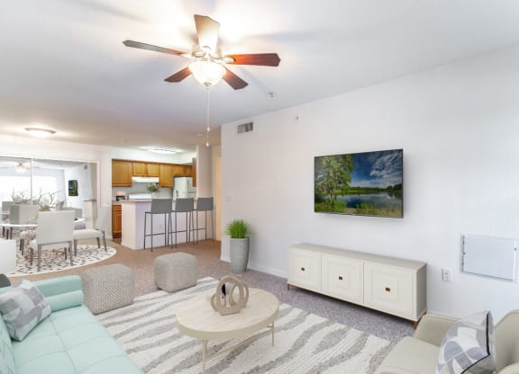 a living room with a ceiling fan and a view of the kitchen and dining area