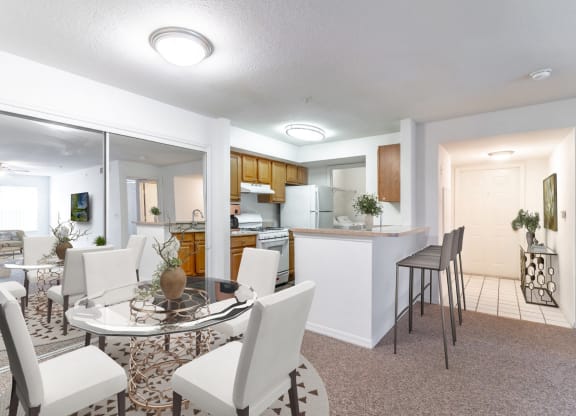 a living room with a table and chairs and a kitchen in the background