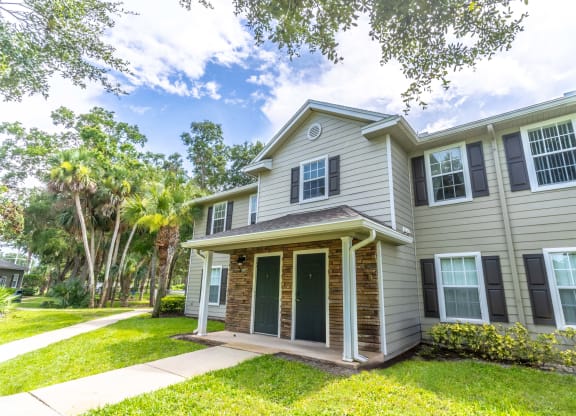 the front of a house with a lawn and palm trees