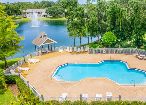 a large swimming pool with a gazebo and a lake in the background