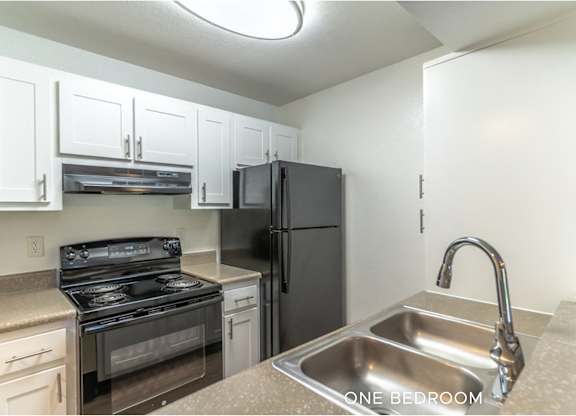 A kitchen with a sink, stove, and refrigerator.